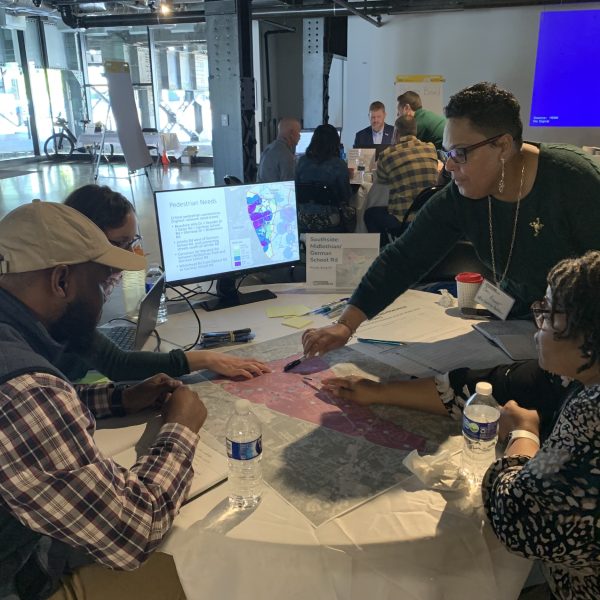 people talking around a computer